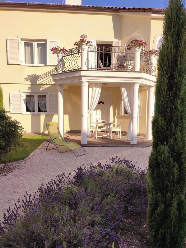 A two-story building with a balcony, a covered patio area, and a seating arrangement.