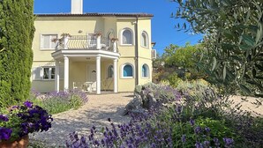 A two-story building with a balcony, surrounded by a garden with lavender plants. - Villa Mandolina Apartments (Zadar)