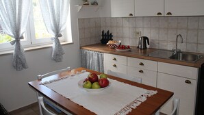 A kitchen with white cabinets, a wooden countertop, a sink, and a window with curtains. - Villa Mandolina Apartments (Zadar)