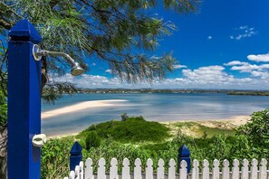 A coastal view with a white picket fence, a blue post, and a metal structure.