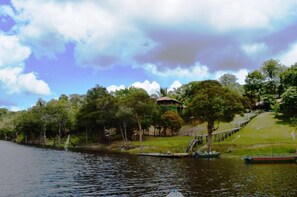 A lakeside view with a gazebo, boats, and a grassy area. - Amazon Tupana Jungle Lodge (Careiro)