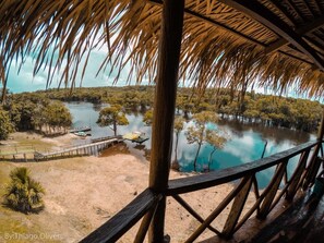 A view from a wooden deck overlooking a river with boats, surrounded by trees and a dock.