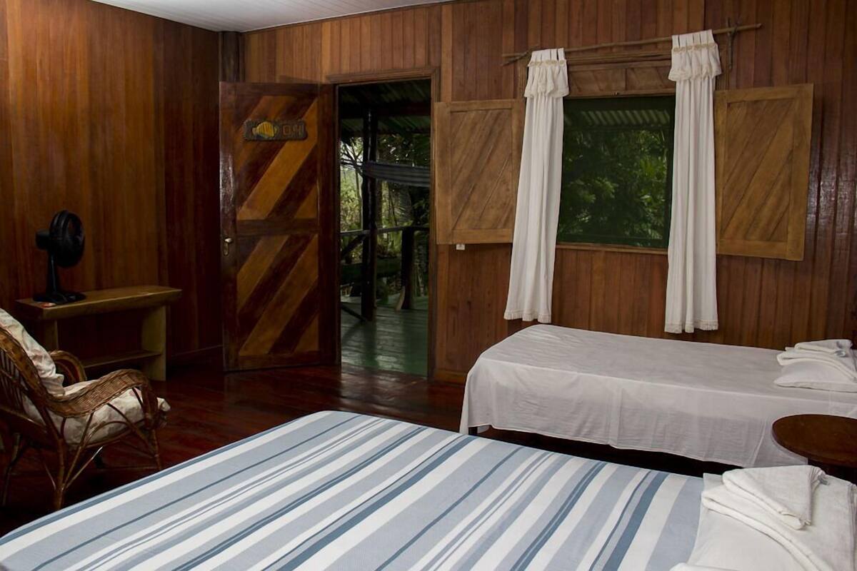Una habitación de madera con dos camas, una silla y una puerta que da al exterior.