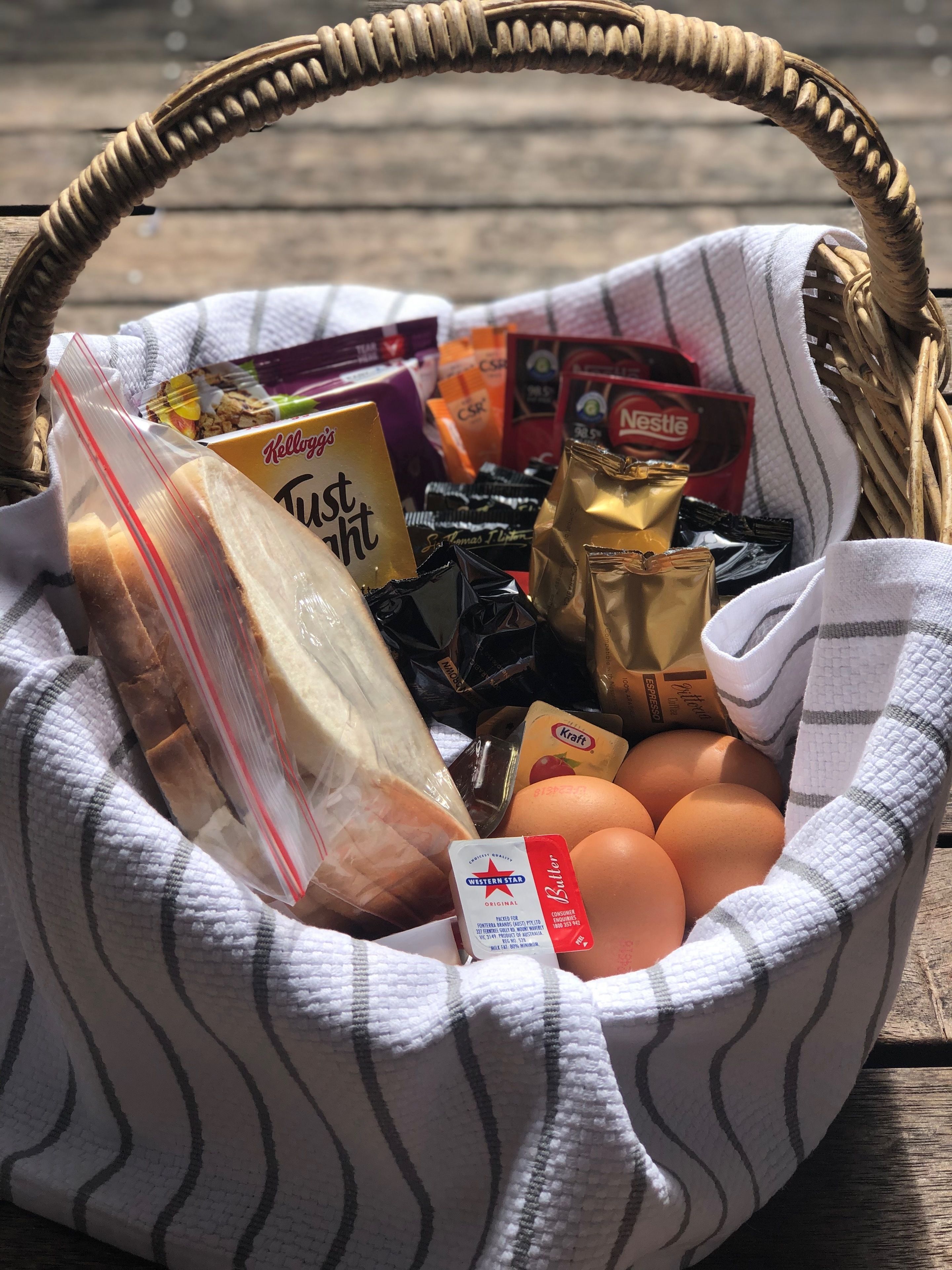 A wicker basket filled with various food items including bread, eggs, and packaged snacks.