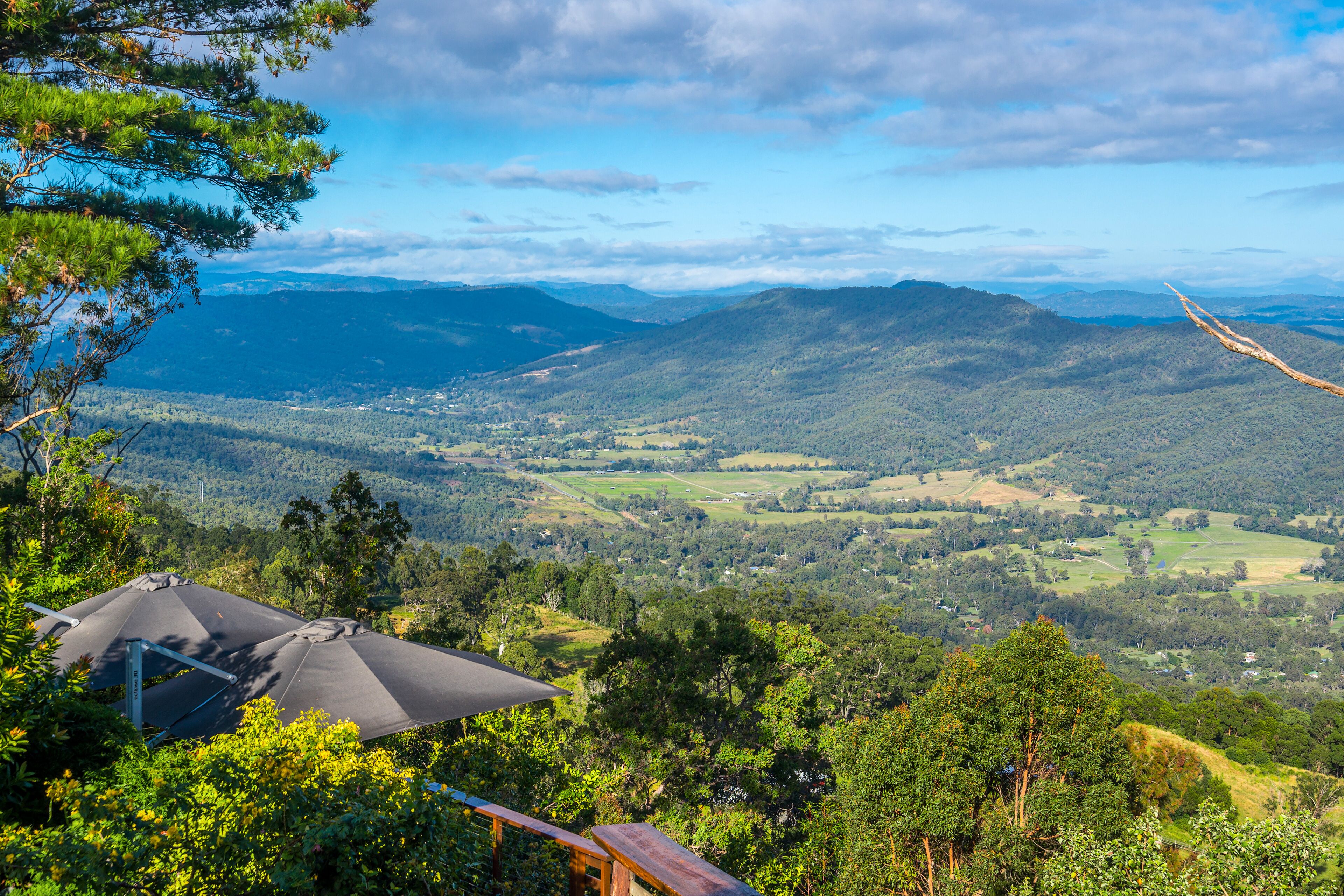 A panoramic view of a mountainous landscape with a wooden deck and a gazebo.