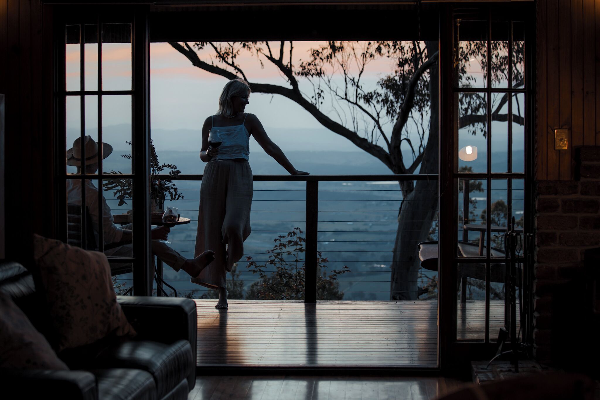 Ein Zimmer mit einer großen Glasschiebetür, die auf einen Balkon mit Blick auf Berge und Bäume führt.