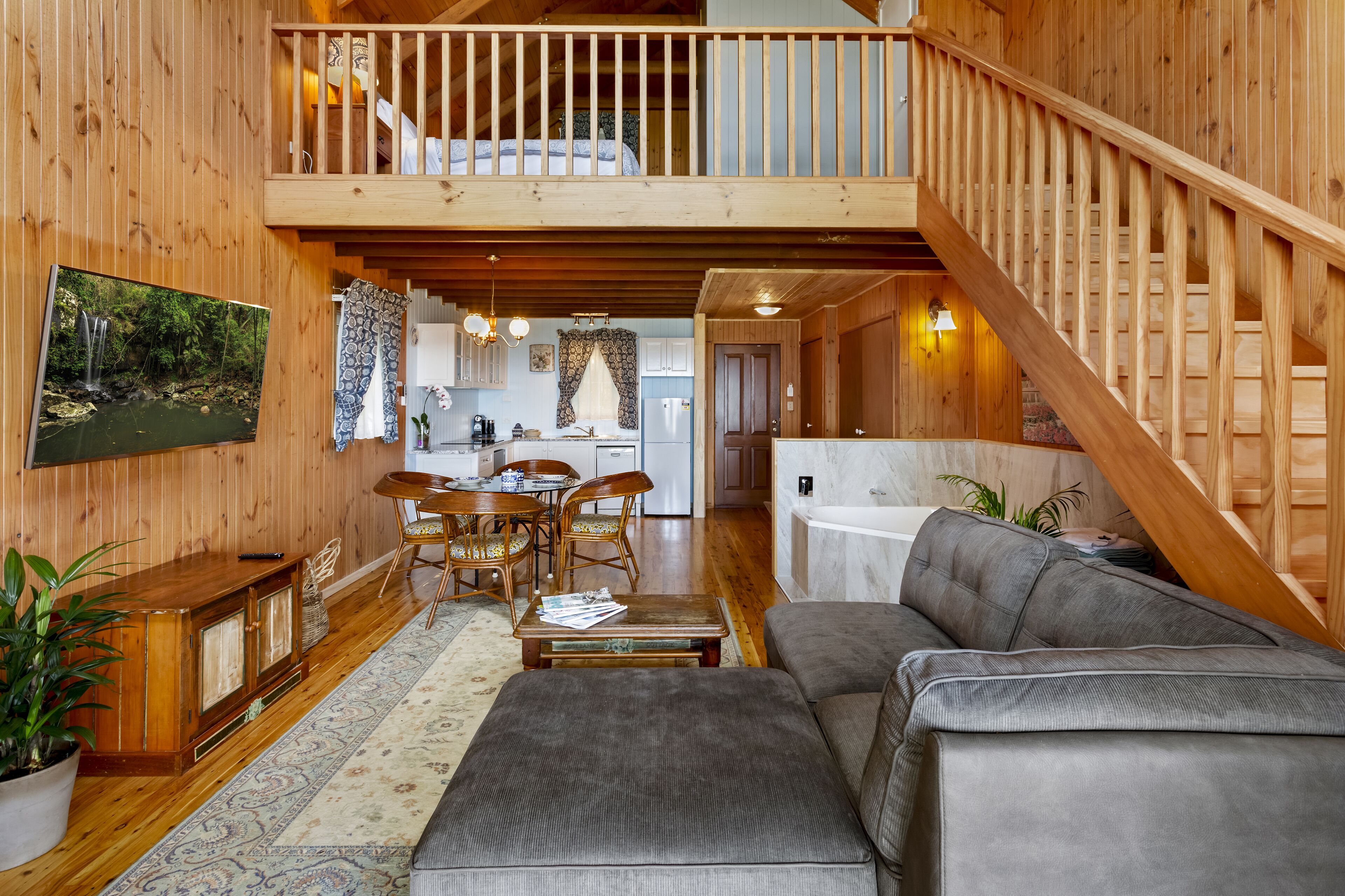 A spacious living area with a wooden staircase, a dining set, and a sofa.