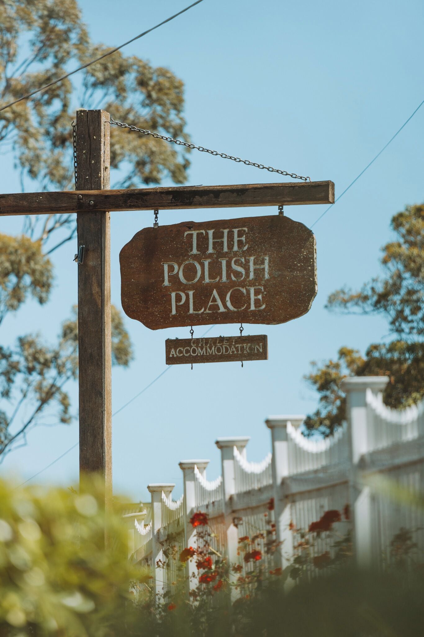 Un cartello di legno con la scritta "THE POLISH PLACE" e "ACCOMMODATION", appeso a un palo.