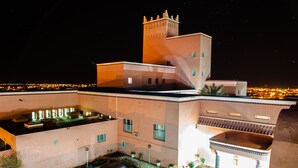 A modern building with a flat roof, a tower with intricate patterns, and a car parked in the driveway. - Hôtel Saghro (Tinghir)