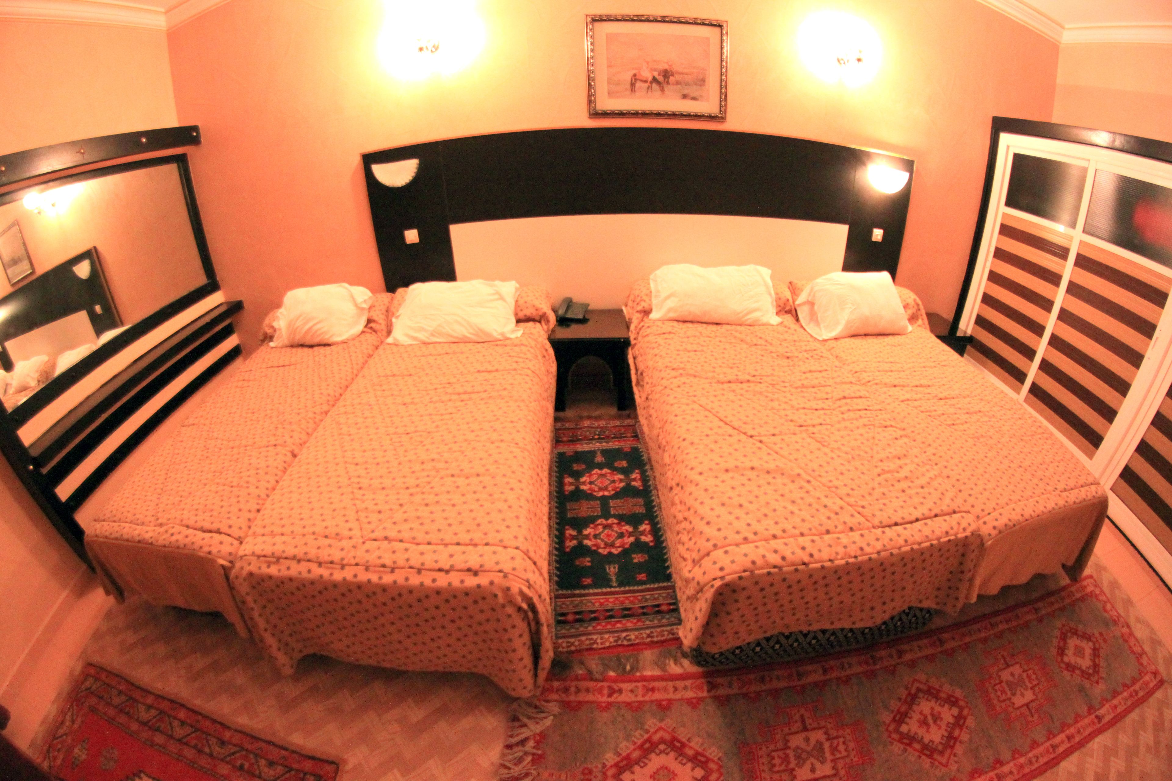 Habitación doble con cama, cabecera, dos mesitas de noche y una mesilla.