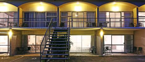 A hotel with a central staircase, multiple balconies, and outdoor seating areas.