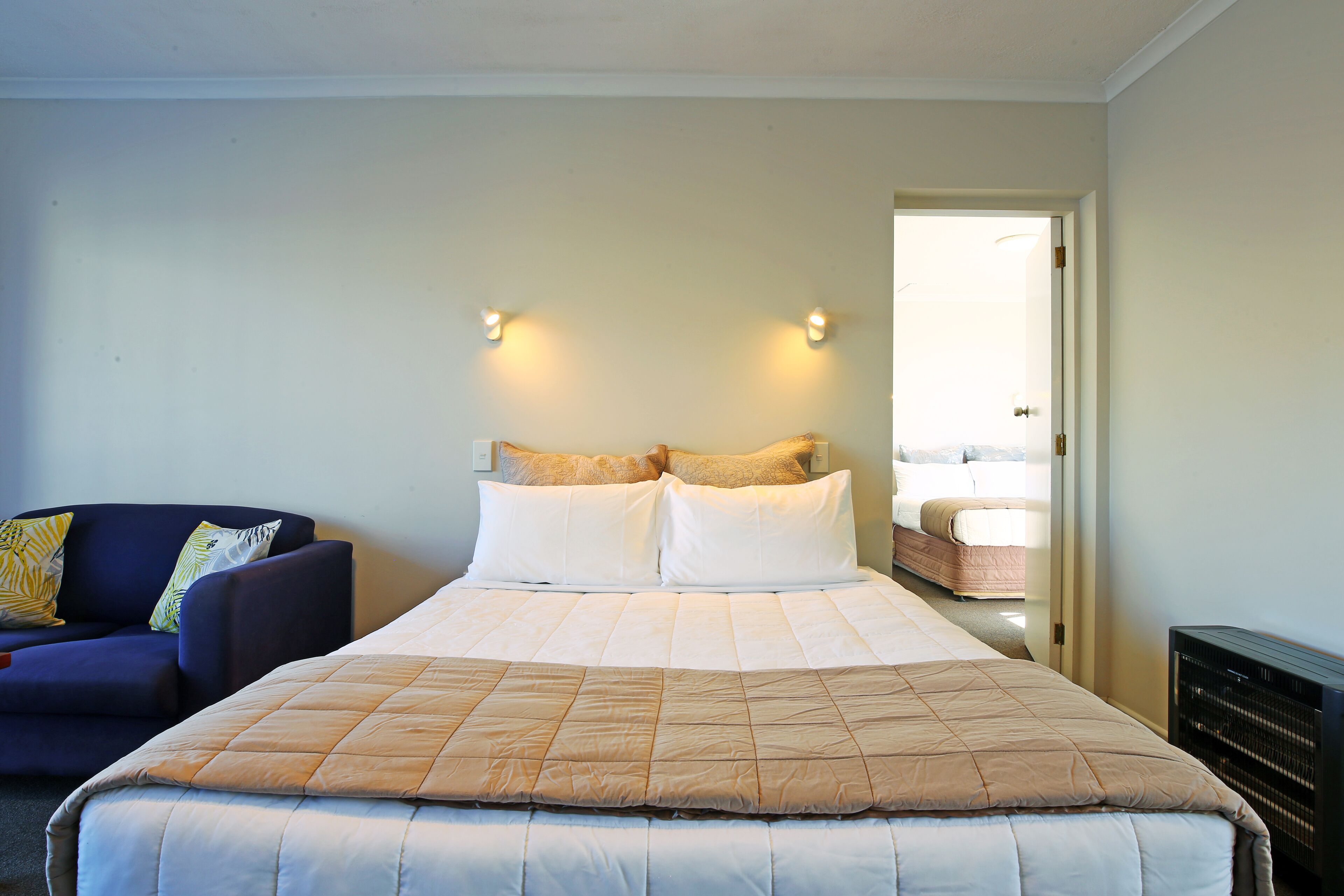 A bedroom with a large bed, a sofa, and a door leading to a bathroom.