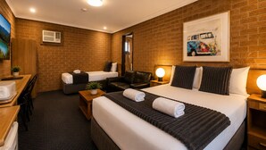 Una habitación de hotel con una cama grande, un escritorio, una silla, un sofá y una pequeña mesa con una planta.