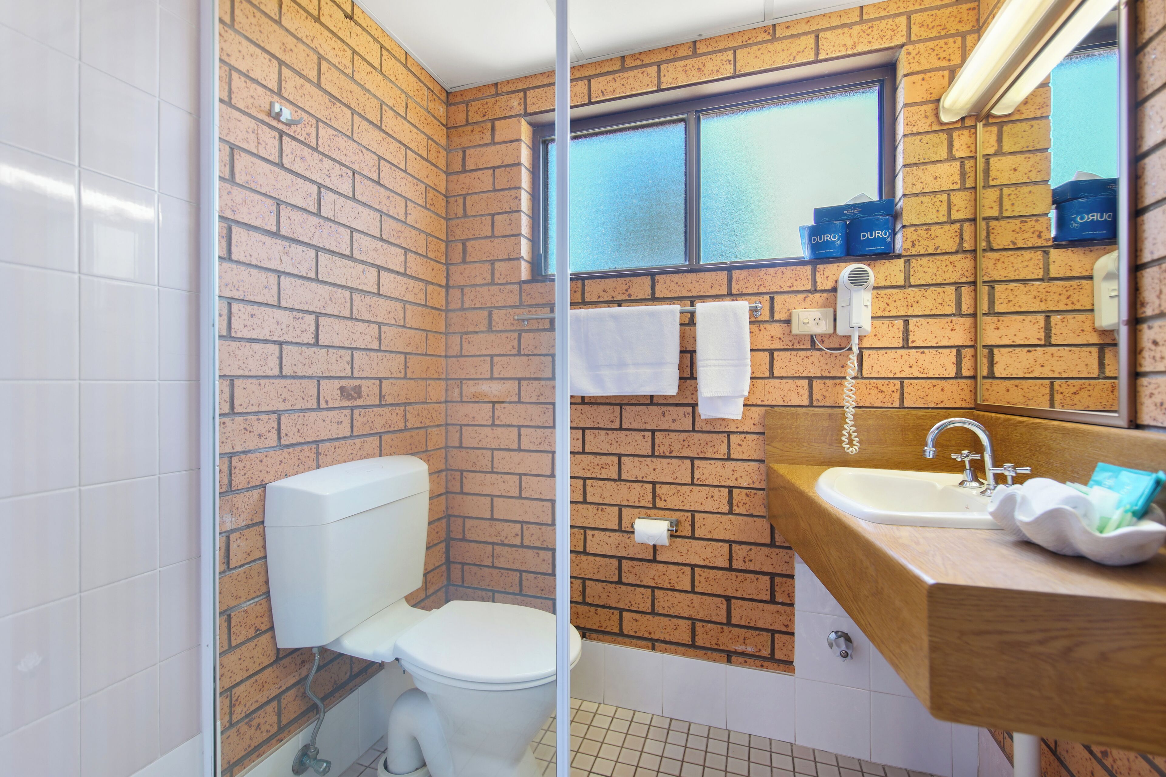 A bathroom with a toilet, sink, and a window.