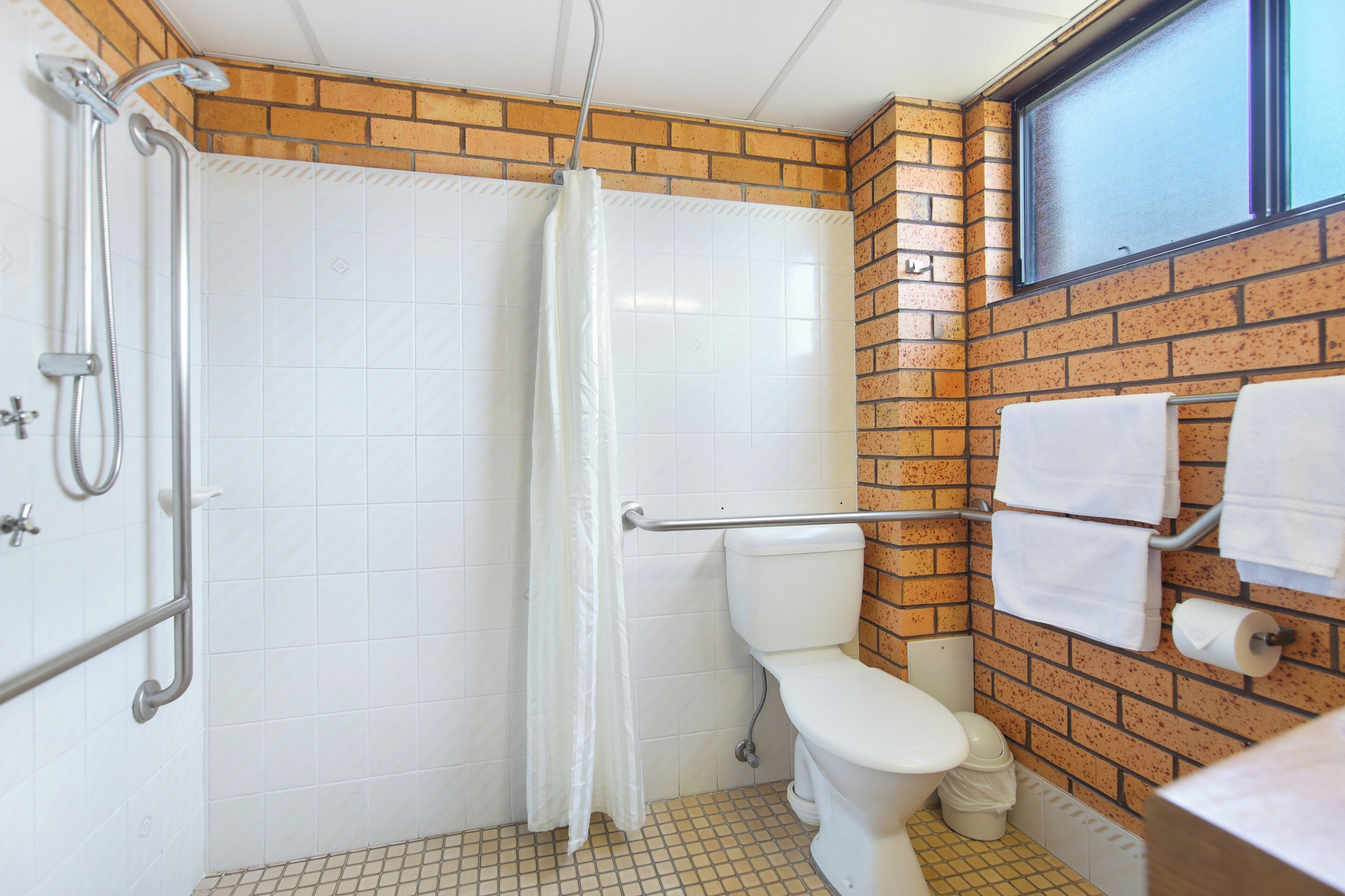 Ein Badezimmer mit Dusche, Toilette und Handtuchhalter.