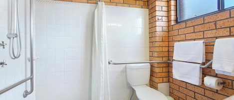 Un baño con ducha, inodoro y toallero.