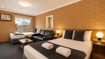 Quarto de hotel com uma cama grande, um sofá, uma mesa de escritório e uma janela com vista.