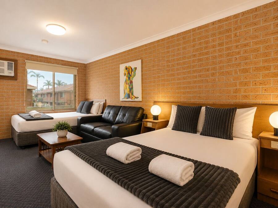 Habitación de hotel con una cama grande, un sofá, un escritorio y una ventana con vistas.
