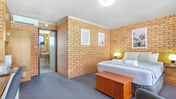Una habitación de hotel con pared de ladrillo, cama, escritorio, silla y baño.