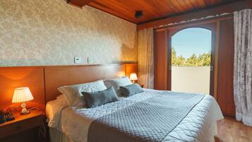 Une chambre d’hôtel avec un lit, deux lampes de chevet, un plafond en bois et une fenêtre avec des rideaux.