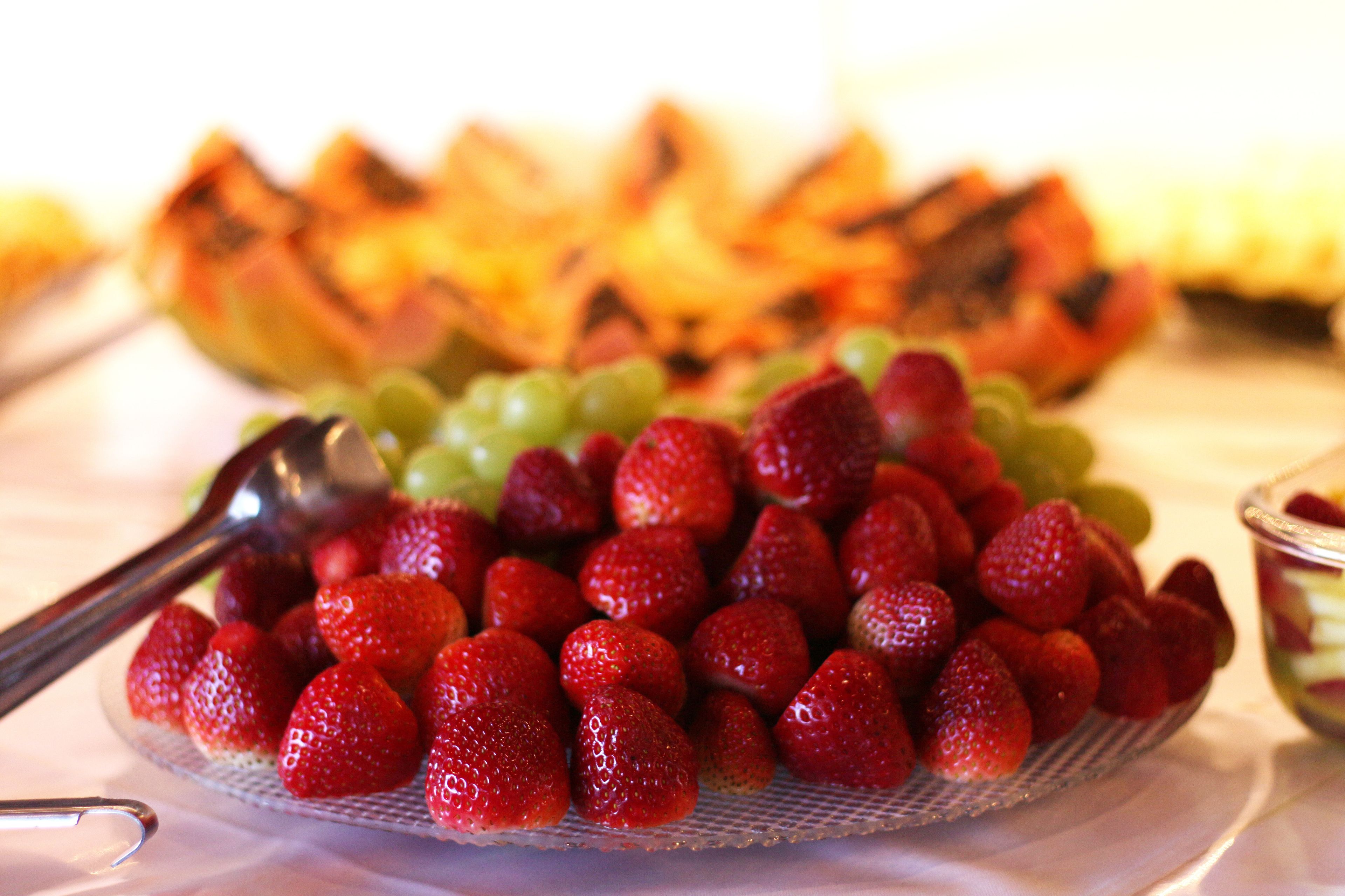 Uma travessa com morangos e uvas sobre uma mesa.