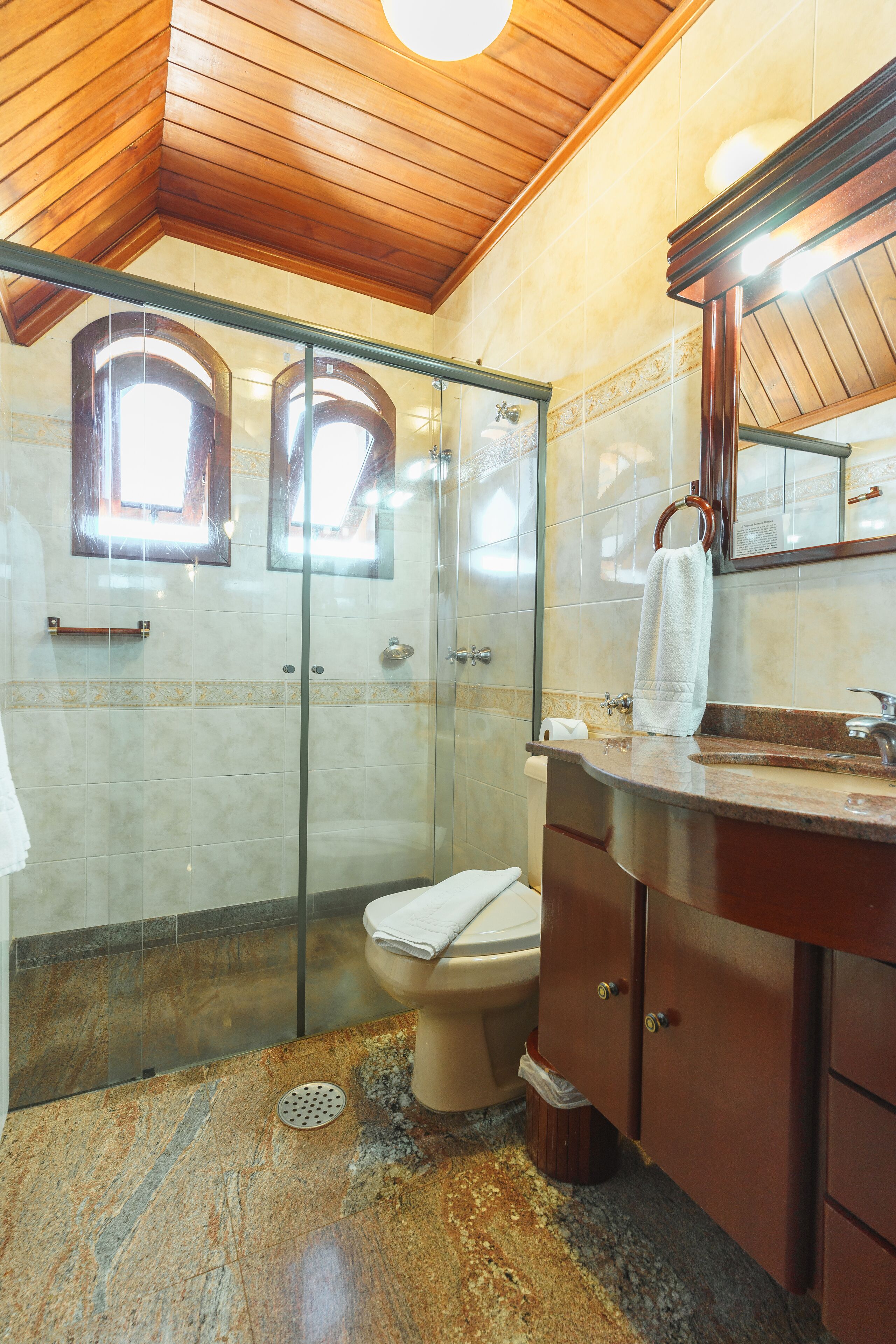 Un bagno con cabina doccia in vetro, un WC e un mobile lavabo con specchio.