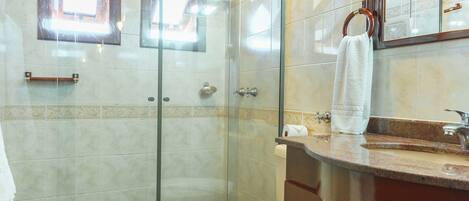 Un bagno con cabina doccia in vetro, un WC e un mobile lavabo con specchio.