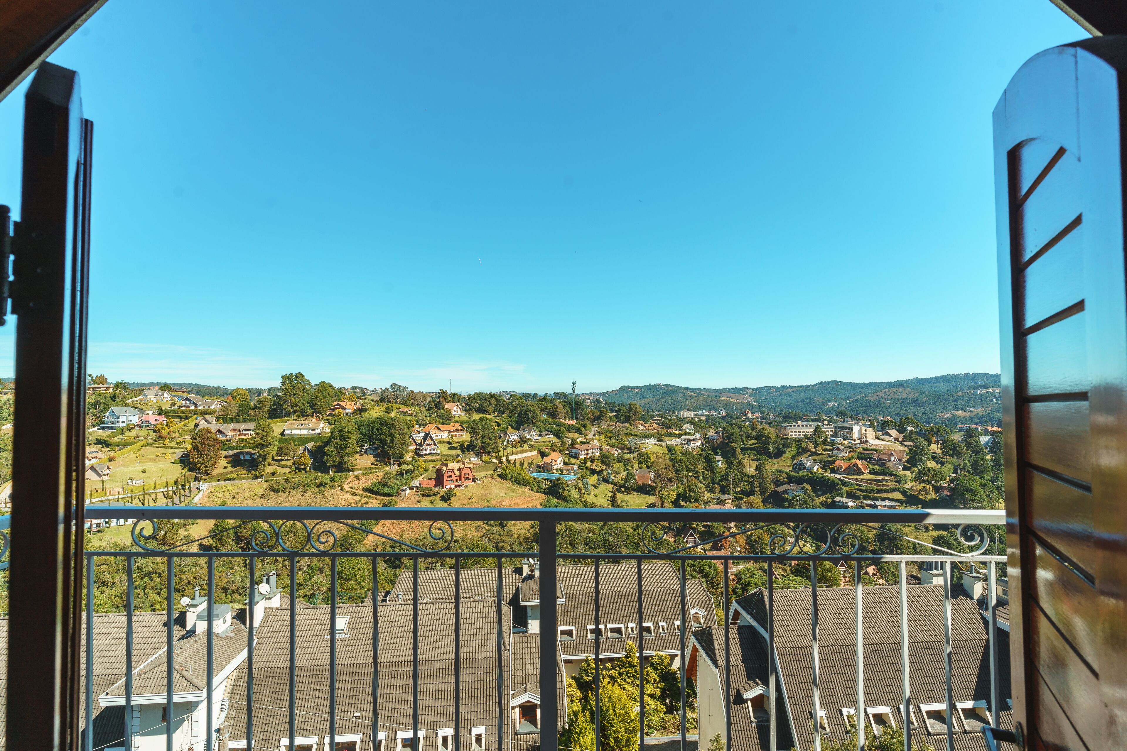 A balcony with a view of a residential area, including houses and greenery.