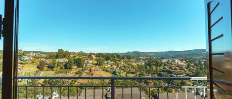A balcony with a view of a residential area, including houses and greenery.