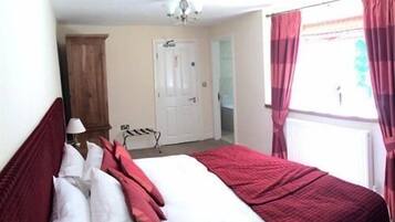 Un dormitorio con cama, mesita de noche, lámpara, puerta y ventana con cortinas.