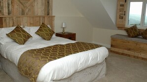 Un dormitorio con cama, mesita de noche, banco y ventana con vistas.
