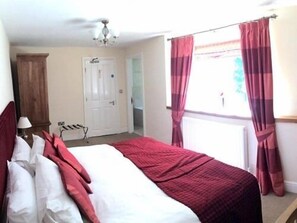 A bedroom with a bed, a wooden wardrobe, a ceiling fan, and a window with curtains.