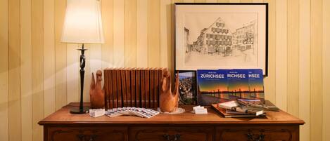 A wooden desk with a lamp, a vase, a framed cityscape, and a book titled "Zürichsee".
