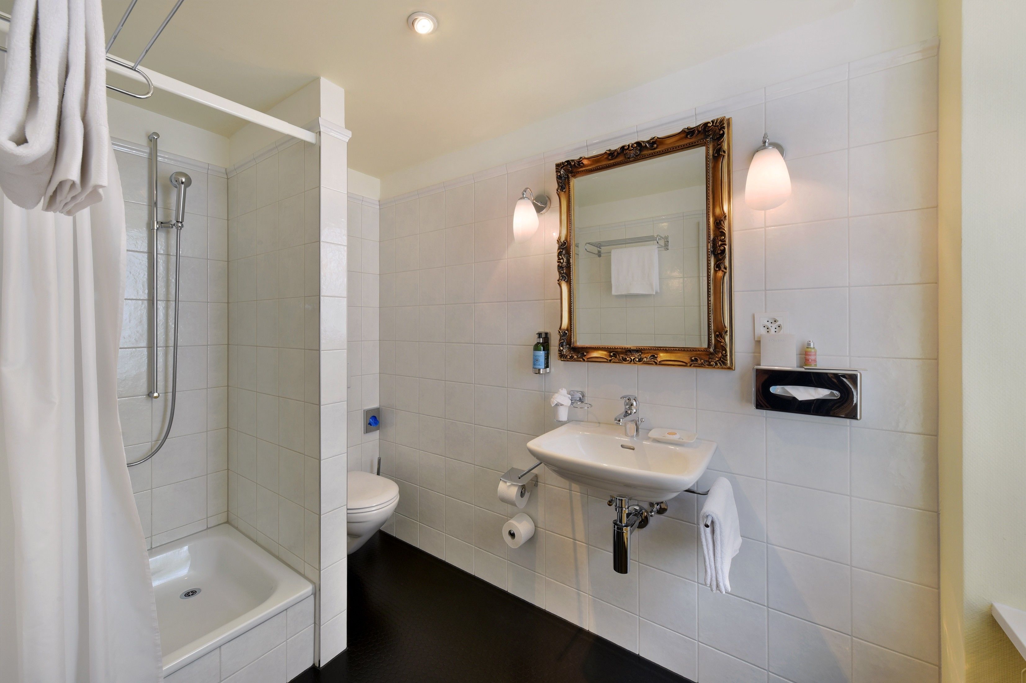 A modern bathroom with a shower, toilet, sink, and a large mirror.