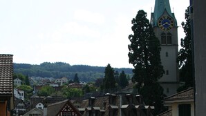 A town with traditional half-timbered houses, a church steeple, and a car parked on the street. - Romantik Hotel Schwan (Horgen)