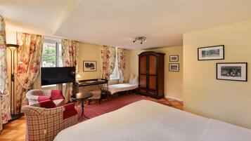 A hotel room with a bed, a desk with a chair, a TV, a wardrobe, and floral curtains.
