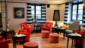 A modern hotel lobby with red seating, black and white striped curtains, and a large window with a view. - Romantik Hotel Schwan (Horgen)