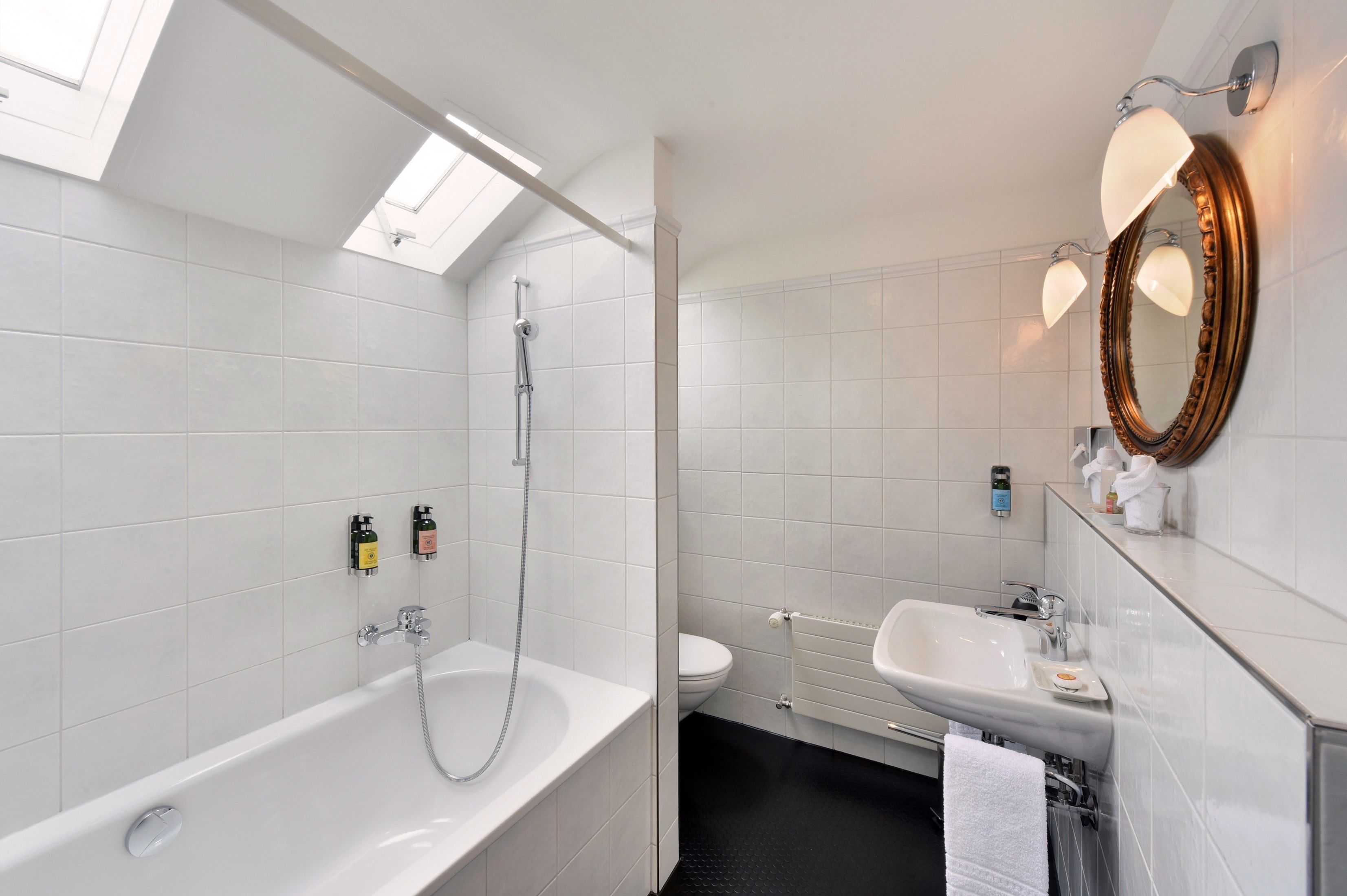 A modern bathroom with a freestanding bathtub, a toilet, a sink, and a mirror with a decorative frame.
