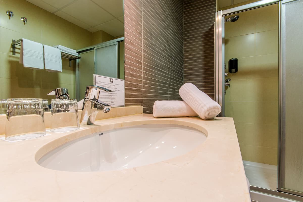 A bathroom with a large sink, a mirror, and a shower.