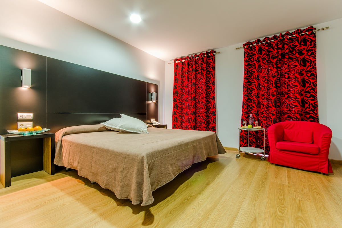 A modern bedroom with a bed, bedside table, and a red chair.