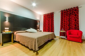 A modern bedroom with a bed, bedside table, and a red chair. - Hotel YIT Alcover (Granada)