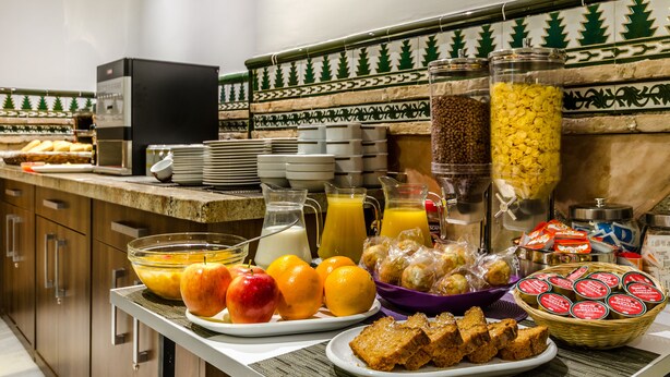 A breakfast buffet with fruits, juices, and pastries. - Hotel YIT Alcover (Granada)