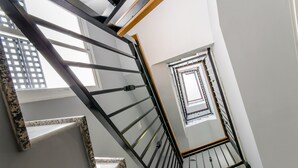 A spiral staircase with a metal railing and a view of a cityscape through a window. - Hotel YIT Alcover (Granada)