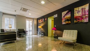 A lobby with a reception desk, seating area, and artwork on the walls. - Hotel YIT Alcover (Granada)