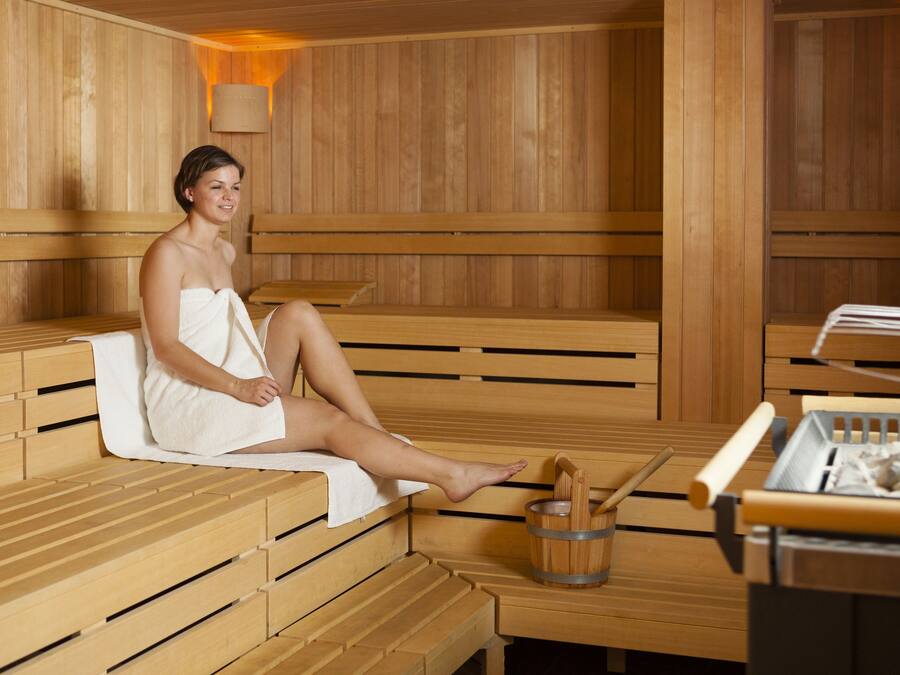 A sauna with wooden benches and a wooden table with a bucket and a towel.