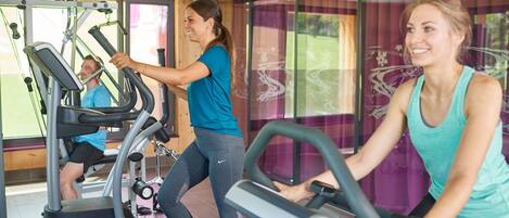 Un gimnasio con bicicletas estáticas y una persona usando una caminadora.