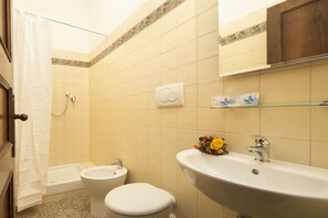 A bathroom with a bathtub, toilet, sink, and shower curtain. - Albergo Tre Donzelle (Siena)