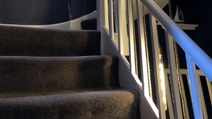 Una escalera con barandilla, un ventanal con vidrieras y un aplique.