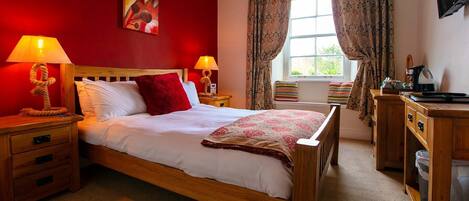 A hotel room with a wooden bed, red walls, and a window with curtains.