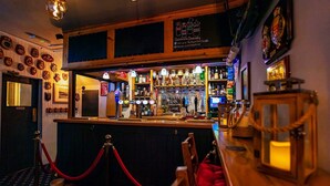Zona de bar con mostrador, varias botellas, vasos y un letrero que dice 'Celebrate Diversity'.